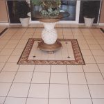 Interesting Hall Design Presented with Single Glass Desk in the Middle Placed Above Floor Tile Patterns